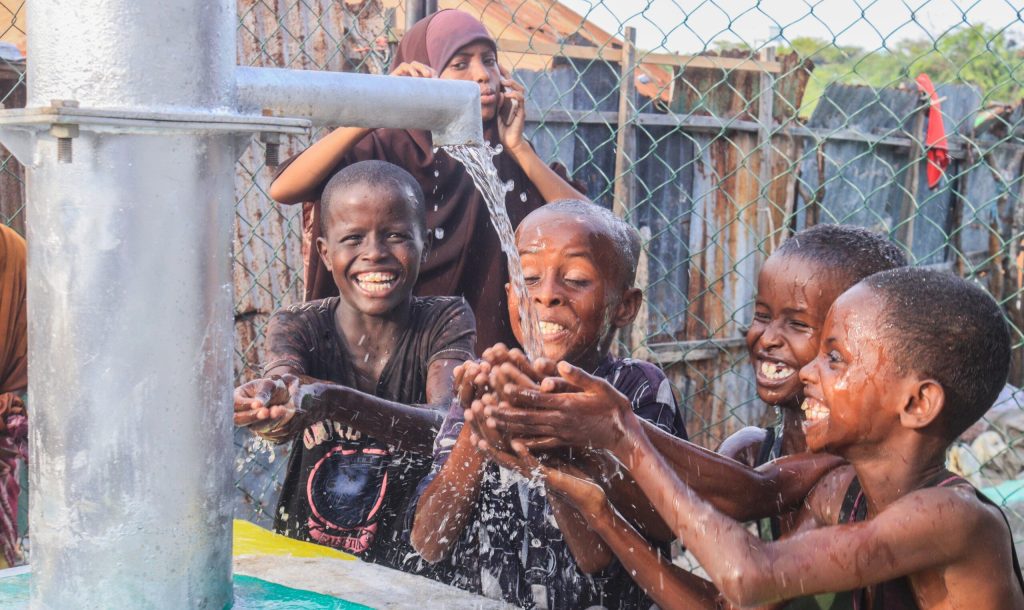 Boys drink water from rehabilitated wells